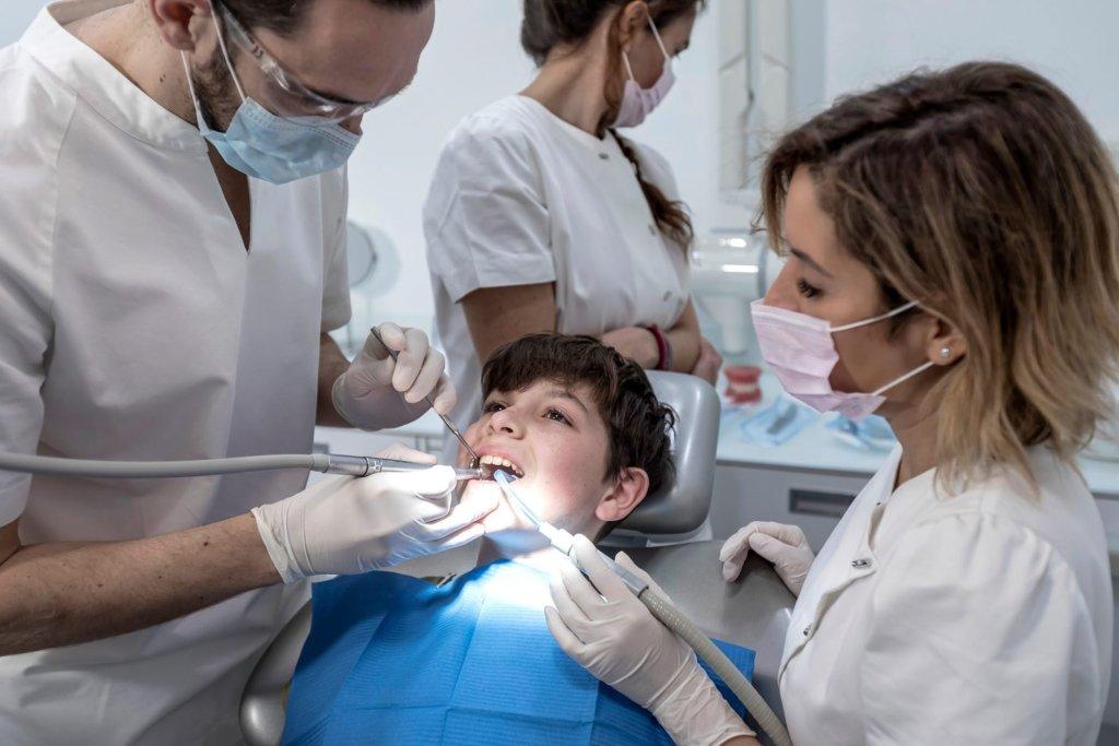 Child Dental Benefits Schedule 19 team of dentists treating a young boy for orthodontics in the dentist s clinic