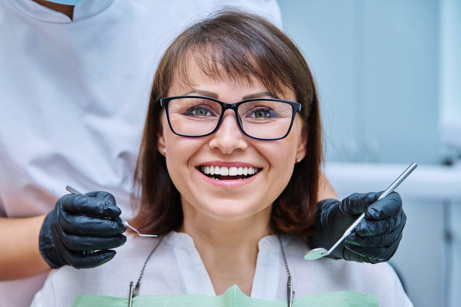 mature woman with teeth in dentistry with hands with dentist examination tools mature woman with teeth in dentistry with hands with dentist examination tools